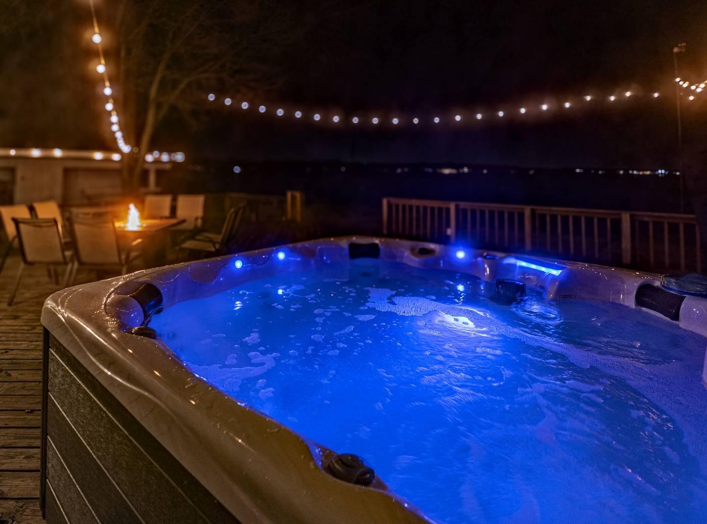 Fire pit and hot tub glowing at night at The Lake House